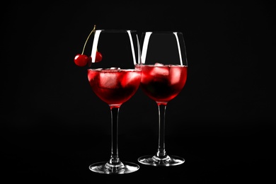 Photo of Delicious cherry wine with ripe juicy berries on black background