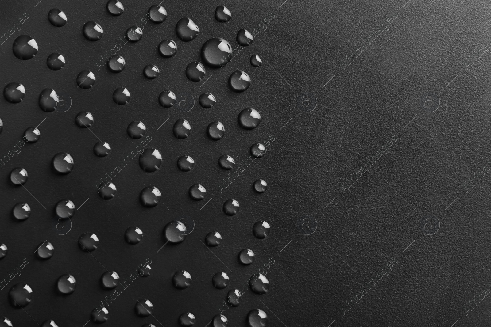 Photo of Water drops on black background, top view. Space for text