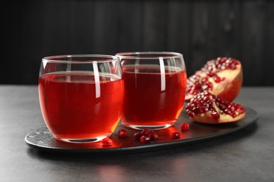 Photo of Tasty pomegranate juice in glasses and fresh fruit on grey table