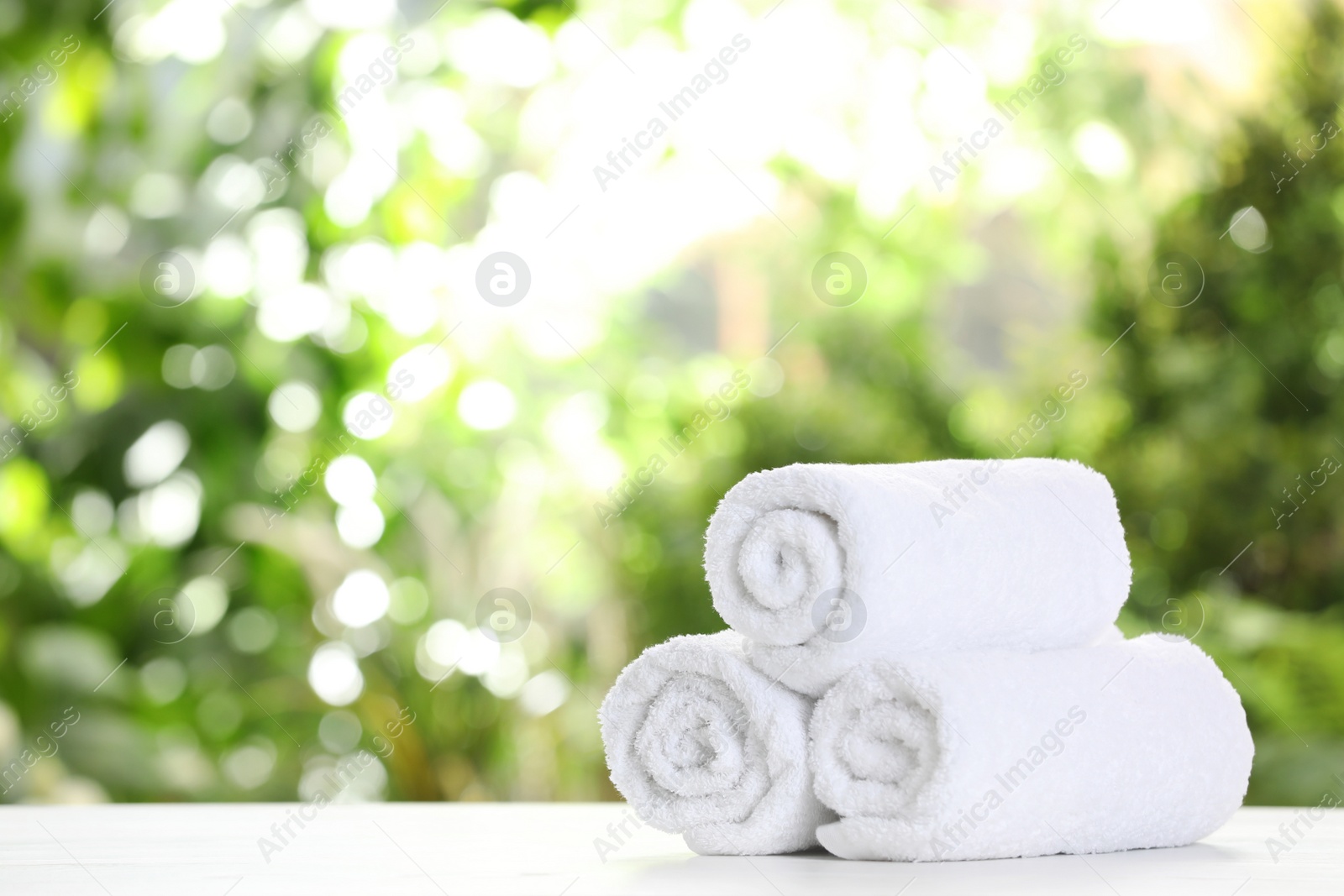 Photo of Soft bath towels on table against blurred background. Space for text