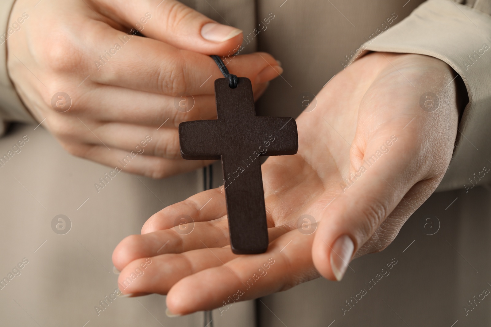 Photo of Woman holding wooden Christian cross, closeup view