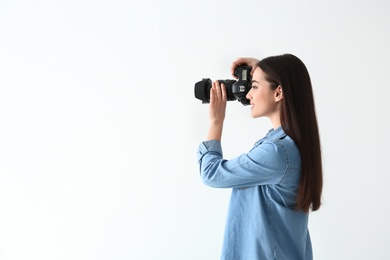 Photo of Female photographer with camera on light background