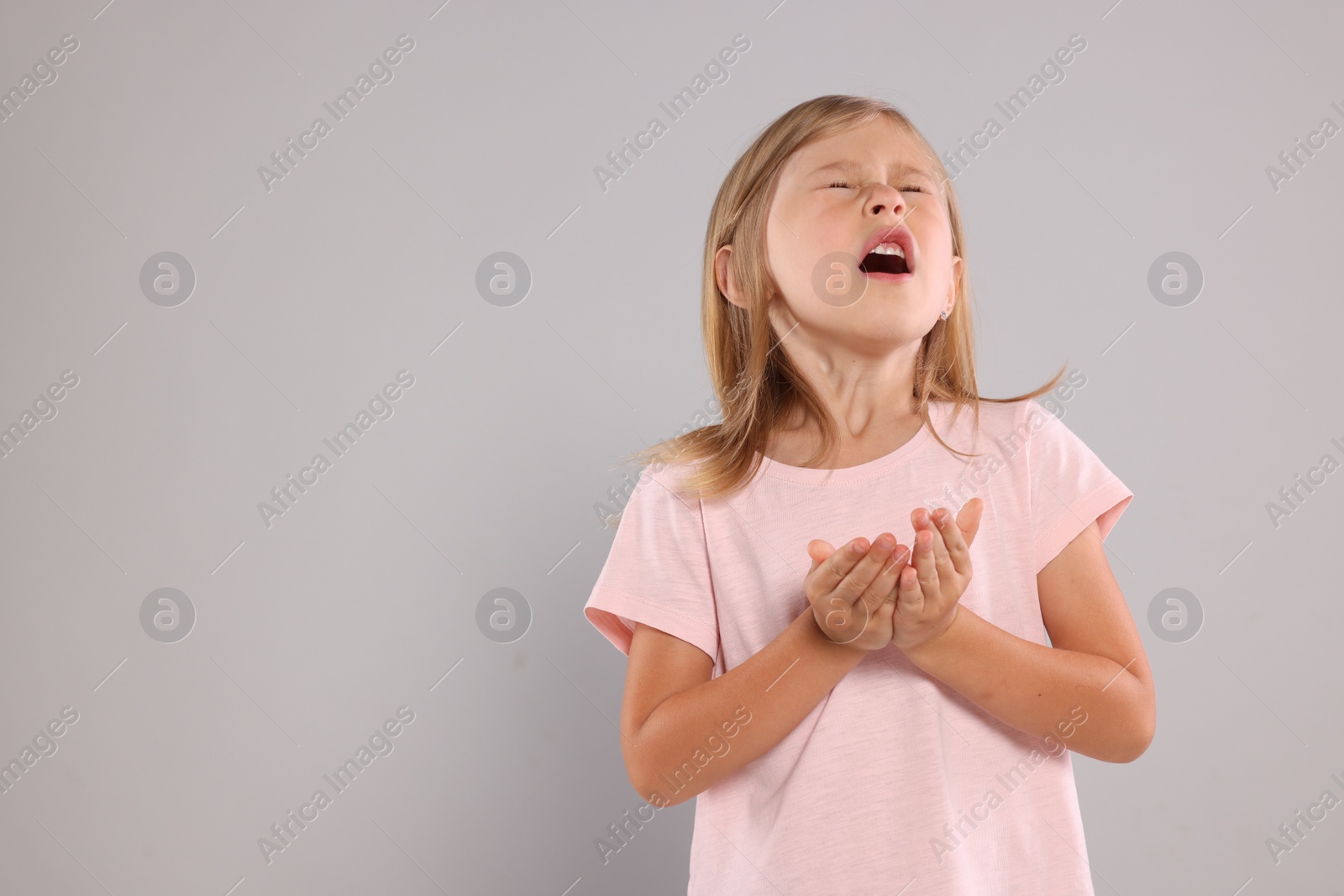 Photo of Suffering from allergy. Little girl sneezing on light gray background, space for text