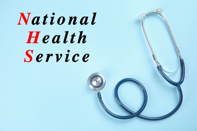 National health service (NHS). Stethoscope and text on light blue background, top view