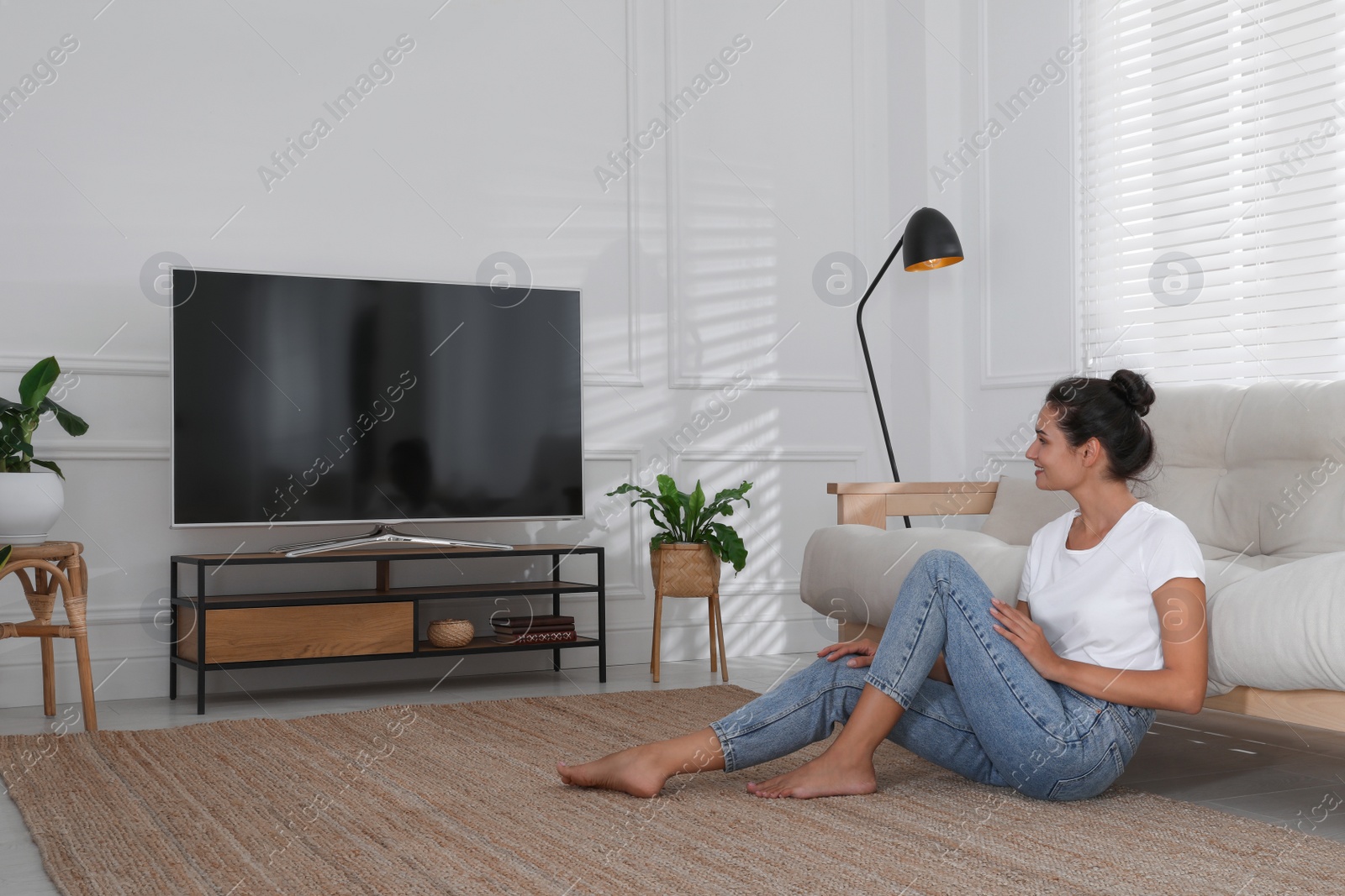 Photo of Woman watching television at home. Living room interior with TV on stand