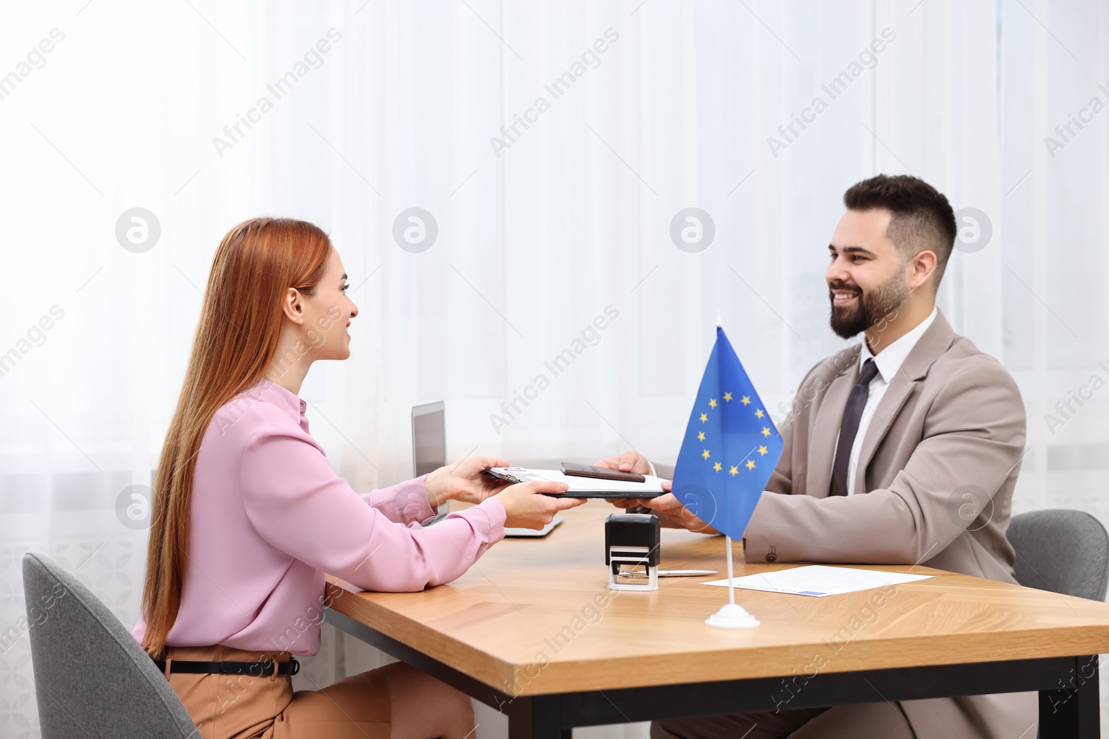 Photo of Immigration to European Union. Woman giving visa application form to embassy worker in office