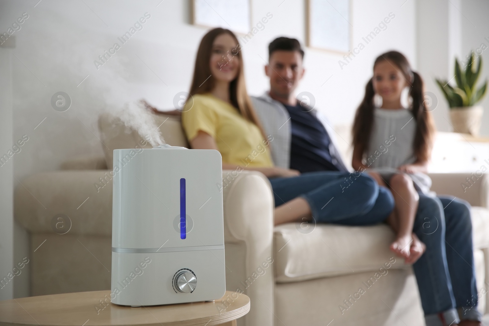 Photo of Modern air humidifier and blurred family on background