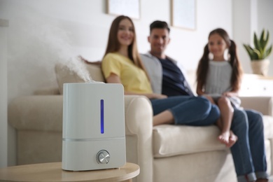 Modern air humidifier and blurred family on background