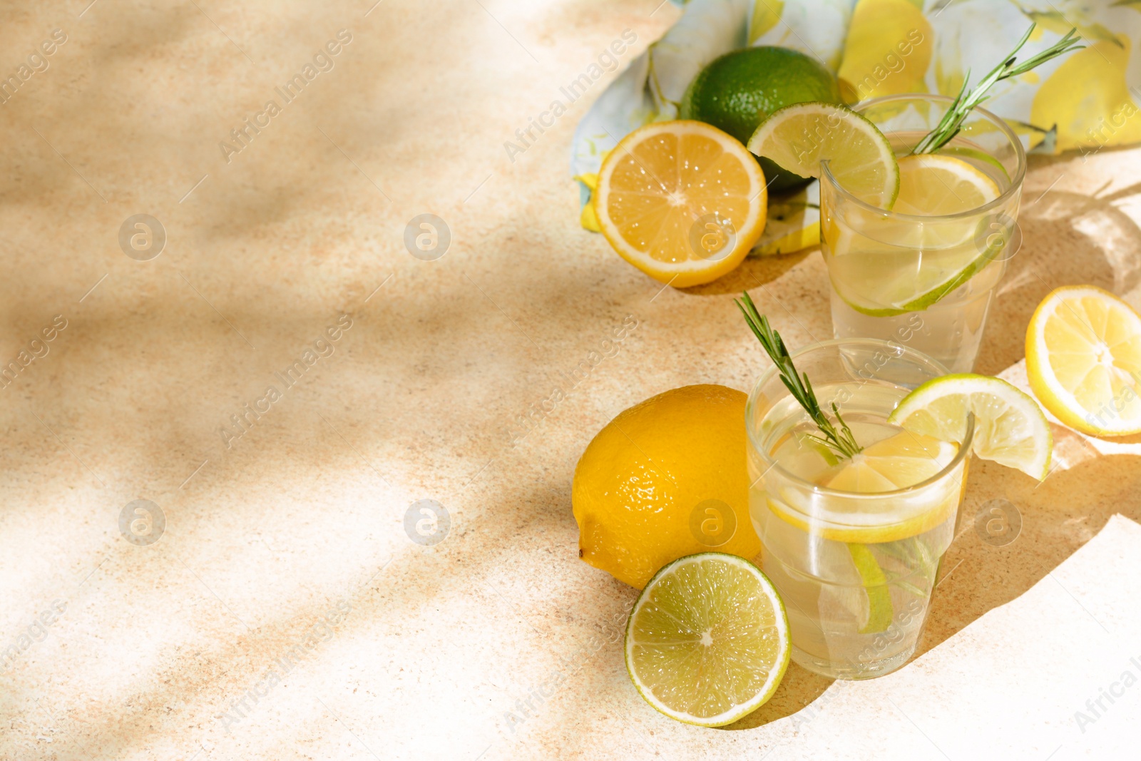 Photo of Glasses of summer refreshing lemonade and ingredients on light table, space for text
