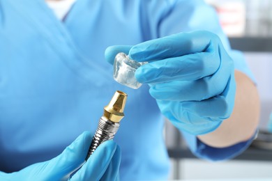 Photo of Dentist putting crown onto abutment of dental implant on blurred background, closeup