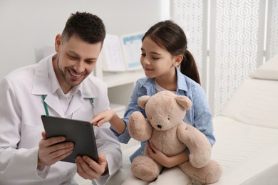 Pediatrician explaining physical examination result to little girl in hospital