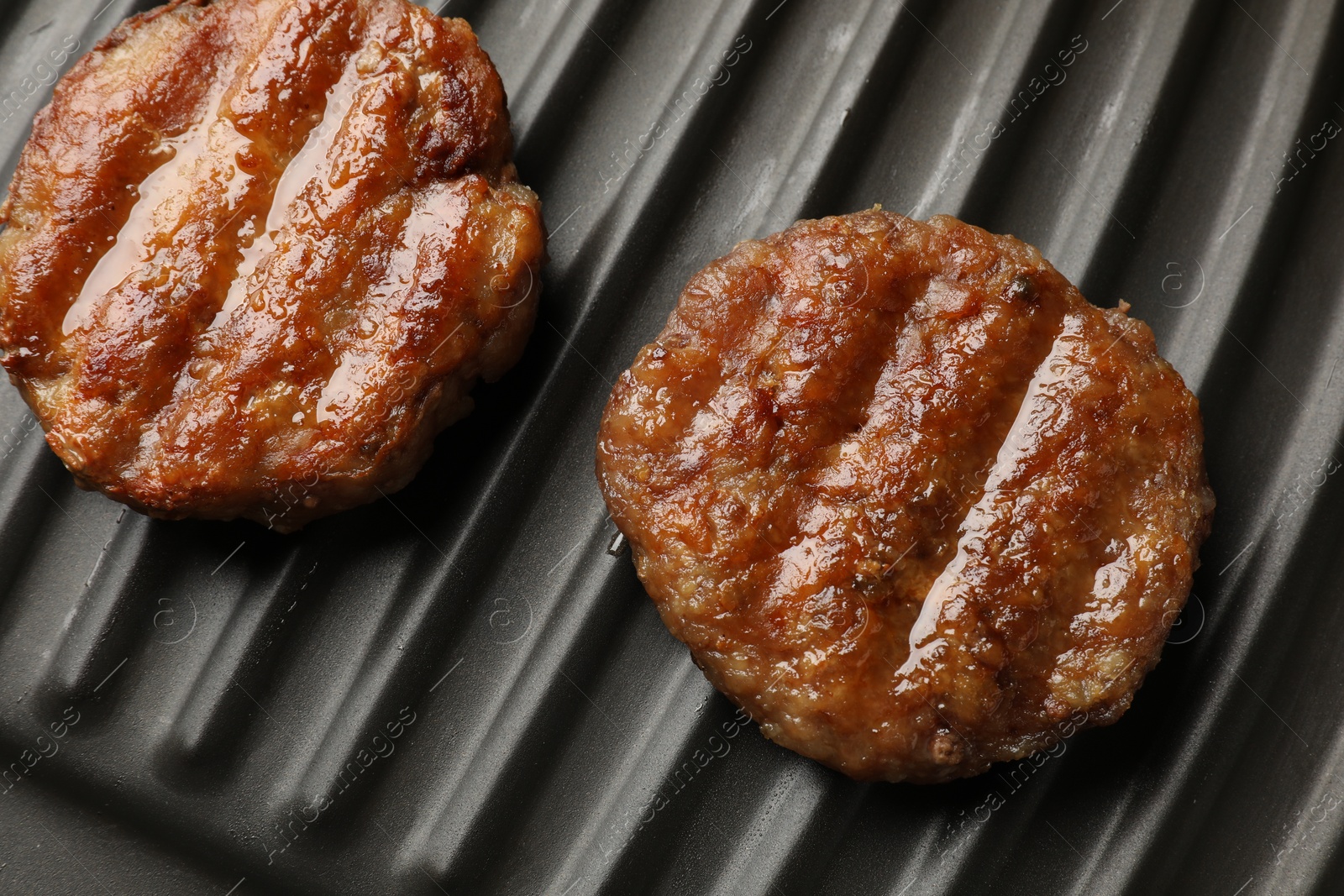 Photo of Delicious hamburger patties on electric grill, closeup