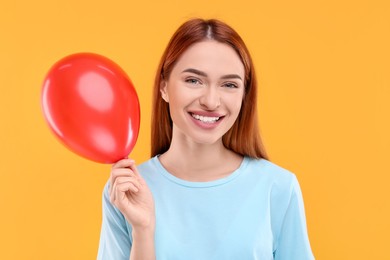 Photo of Happy woman with red balloon on orange background