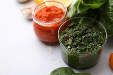 Photo of Different marinades in tableware on light table, closeup. Space for text