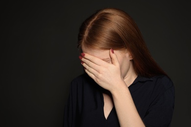 Photo of Upset young woman crying against dark background. Space for text