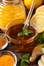 Tea with honey and ingredients on wooden table