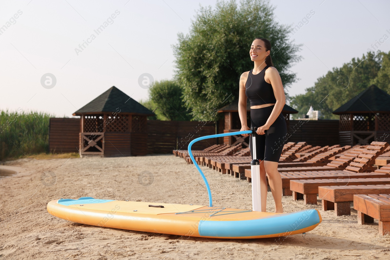 Photo of Woman pumping up SUP board on river shore