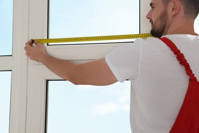 Worker measuring window with tape indoors, closeup. Roller blinds installation