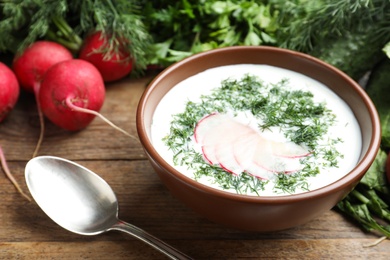 Photo of Delicious cold summer soup with kefir served on wooden table