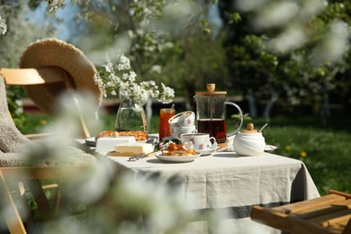 Photo of Beautiful table setting with spring flowers in garden on sunny day