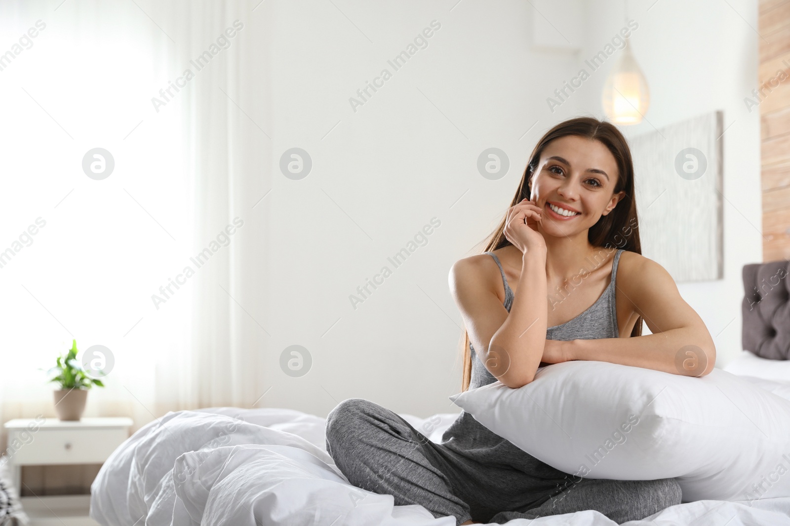 Photo of Portrait of beautiful young woman sitting on large bed