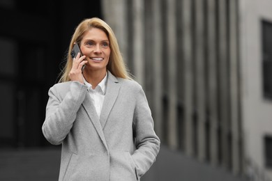 Photo of Smiling woman talking on smartphone outdoors, space for text. Lawyer, businesswoman, accountant or manager