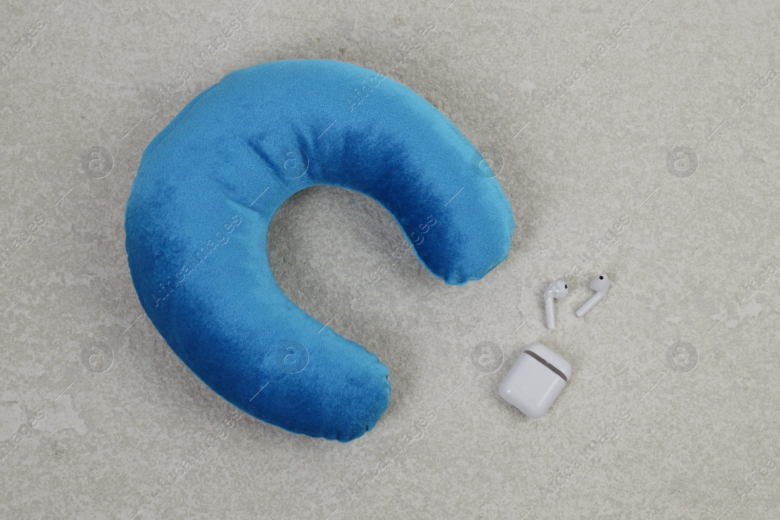 Photo of Soft travel pillow and earphones on grey textured background, top view