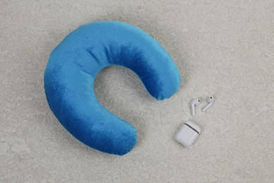 Photo of Soft travel pillow and earphones on grey textured background, top view