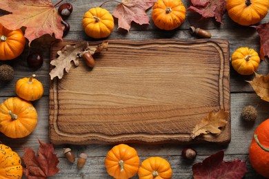 Photo of Thanksgiving day. Flat lay composition with pumpkins and wooden board on table, space for text