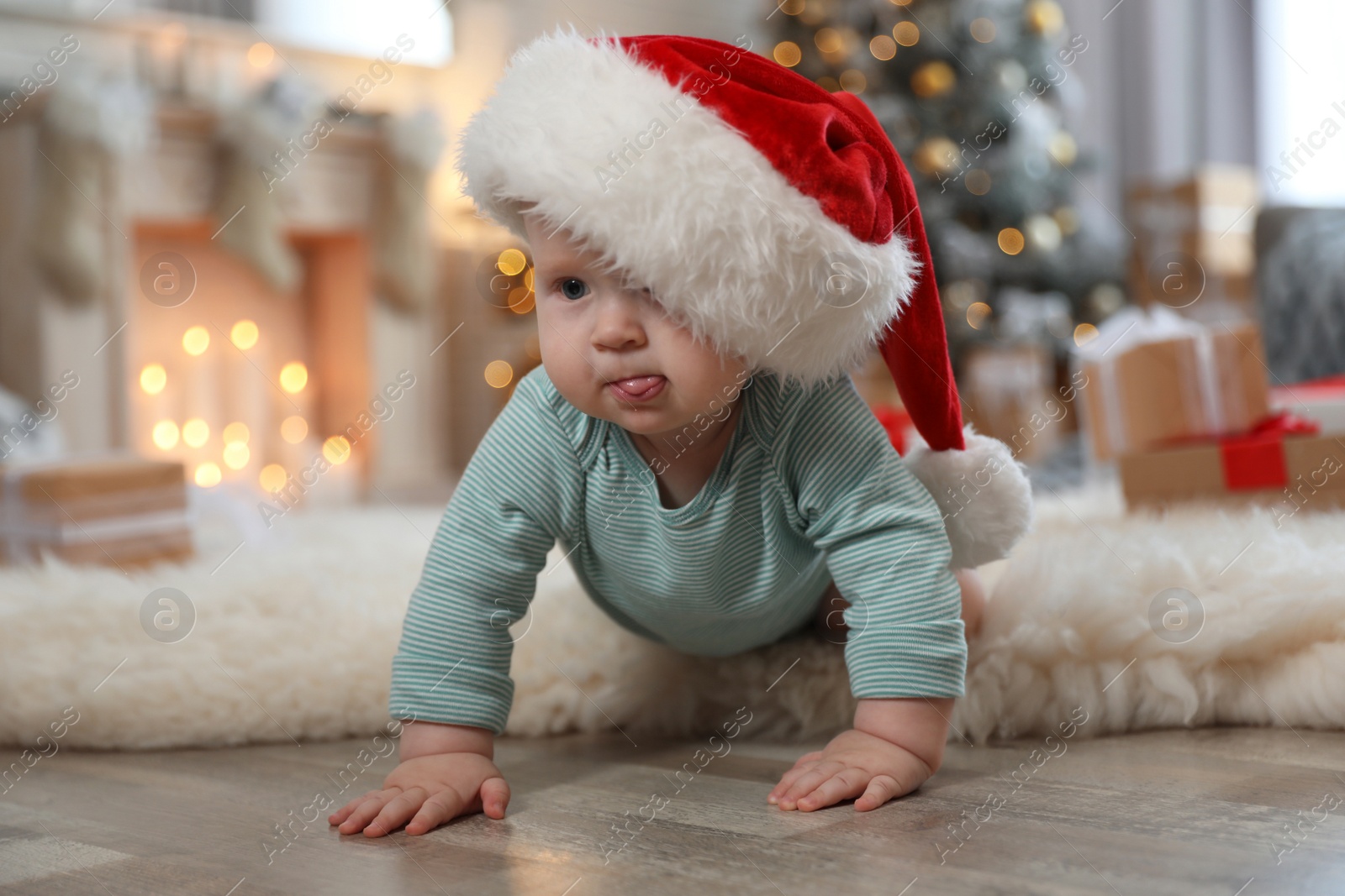 Image of Cute baby in Santa hat crawling on floor. First Christmas