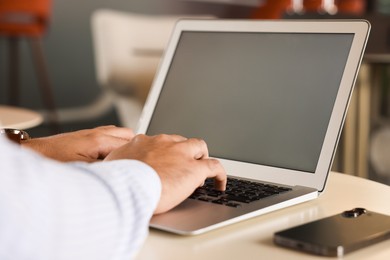 Photo of Man working on laptop at table in office, closeup