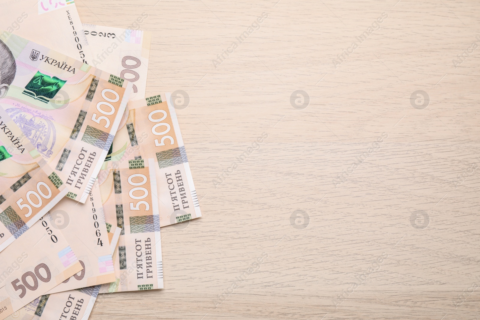 Photo of Ukrainian money on wooden background, flat lay. Space for text