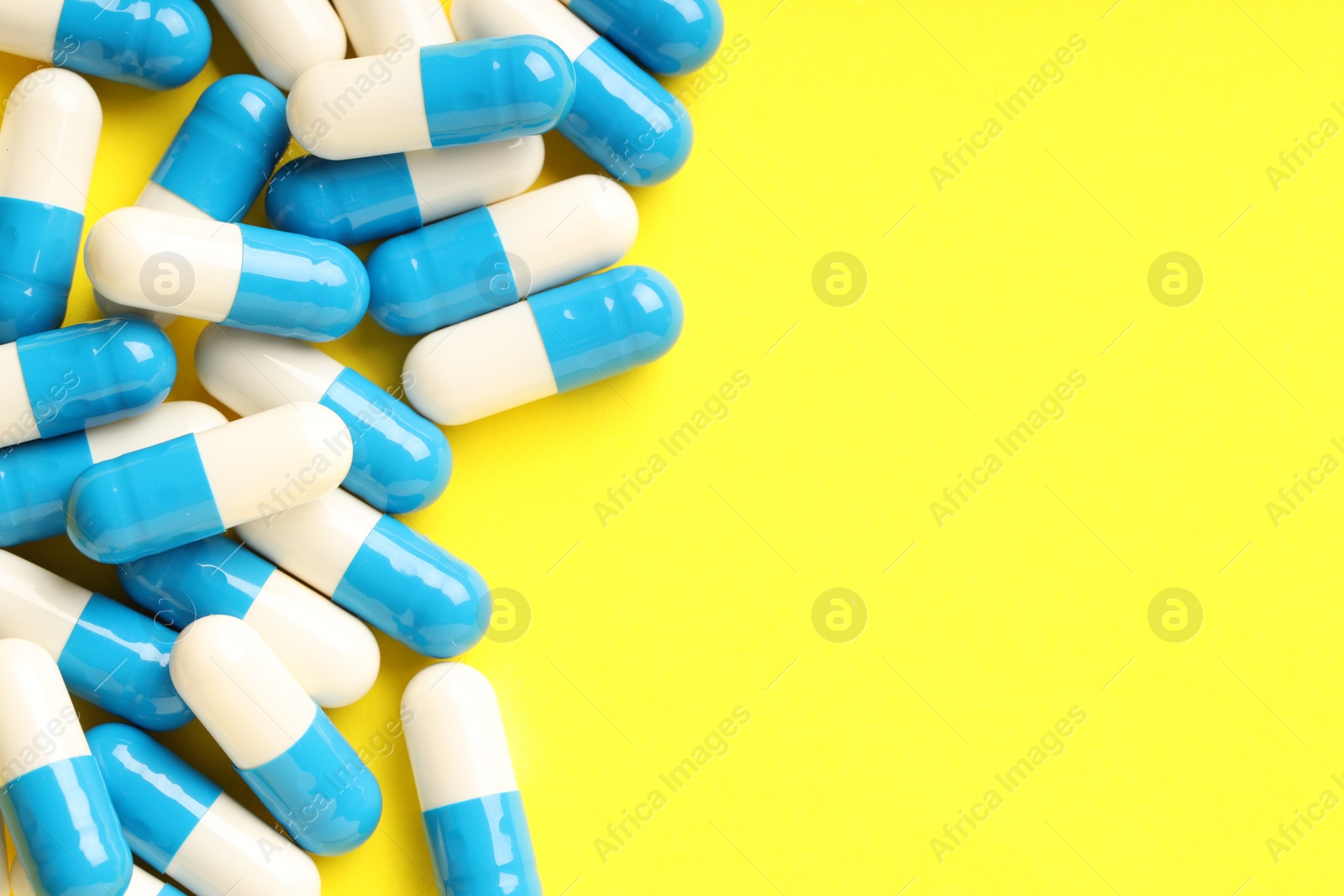 Photo of Many antibiotic pills on light blue background, top view. Space for text