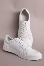 Photo of Pair of stylish white sneakers on grey background