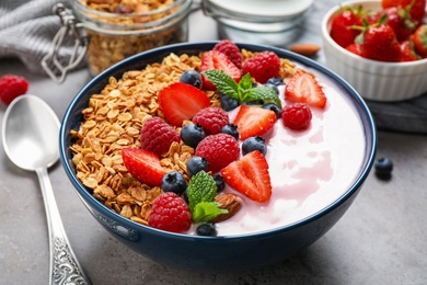 Photo of Tasty homemade granola with yogurt on grey table, closeup. Healthy breakfast