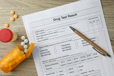 Photo of Drug test result form, container with urine sample and pills on wooden table, flat lay