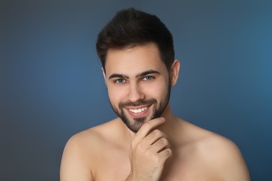Handsome young man with beard after shaving on blue background