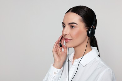 Hotline operator with modern headset on light grey background, space for text. Customer support