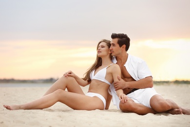 Photo of Happy young couple relaxing together on sea beach at sunset