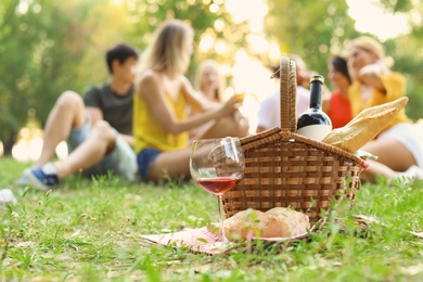 Photo of Basket with food prepared for picnic in park and blurred people on background