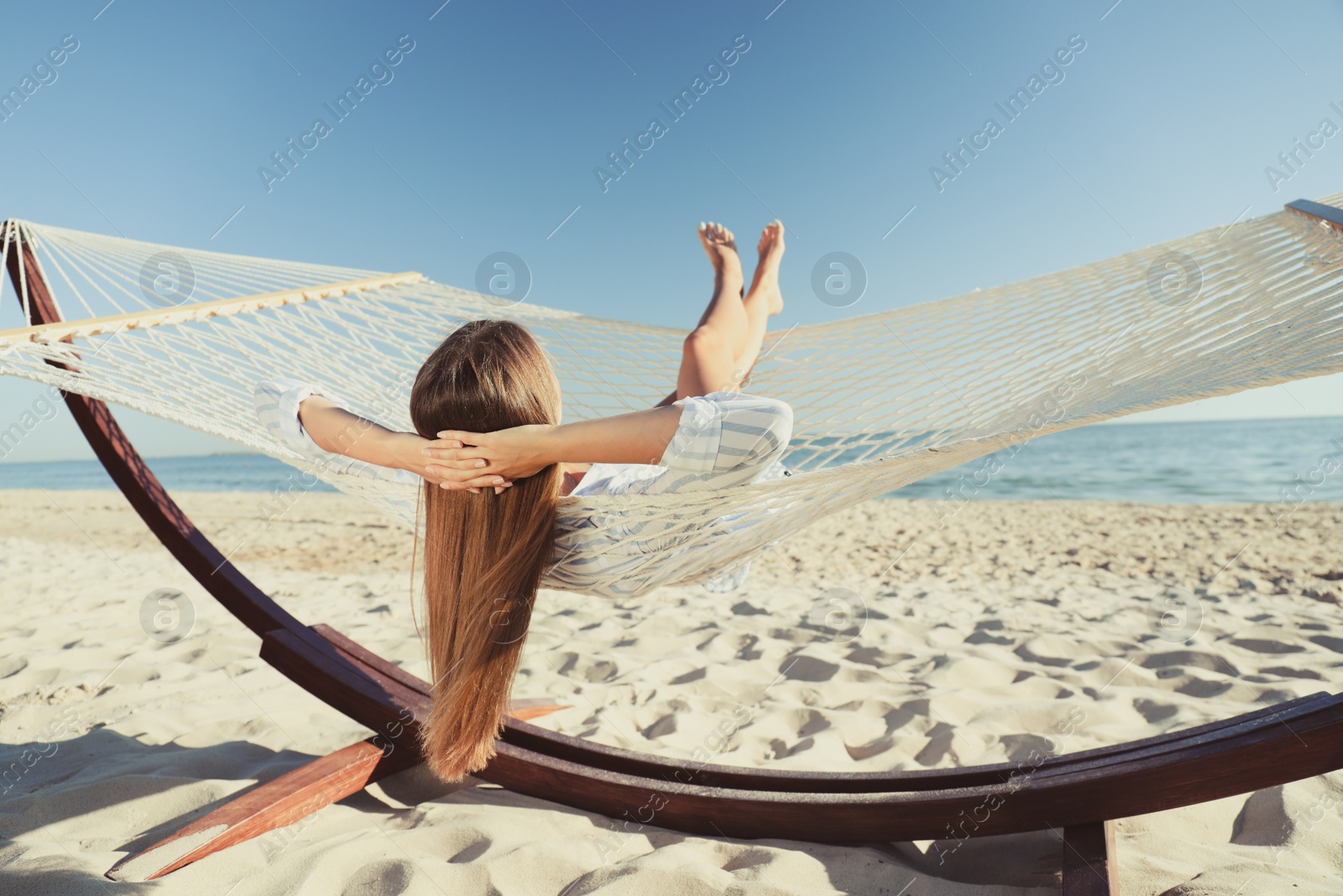 Photo of Young woman relaxing in hammock on beach