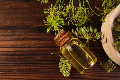 Photo of Bottle of essential oil and fresh dill on wooden table, flat lay. Space for text