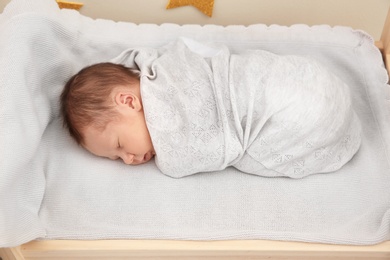 Adorable newborn baby sleeping in small bed