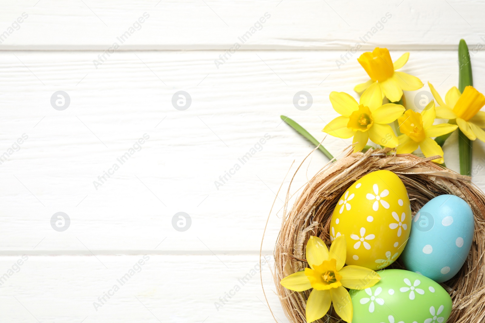 Photo of Flat lay composition with Easter eggs on white wooden background. Space for text