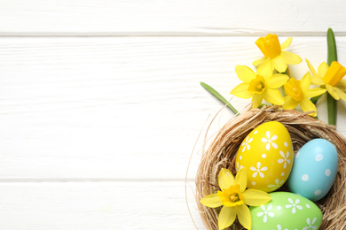 Photo of Flat lay composition with Easter eggs on white wooden background. Space for text