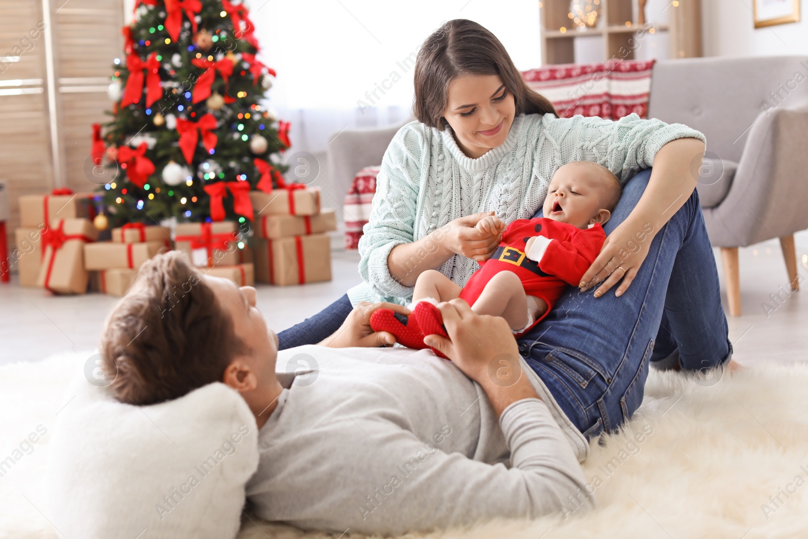 Photo of Happy couple with baby celebrating Christmas together at home