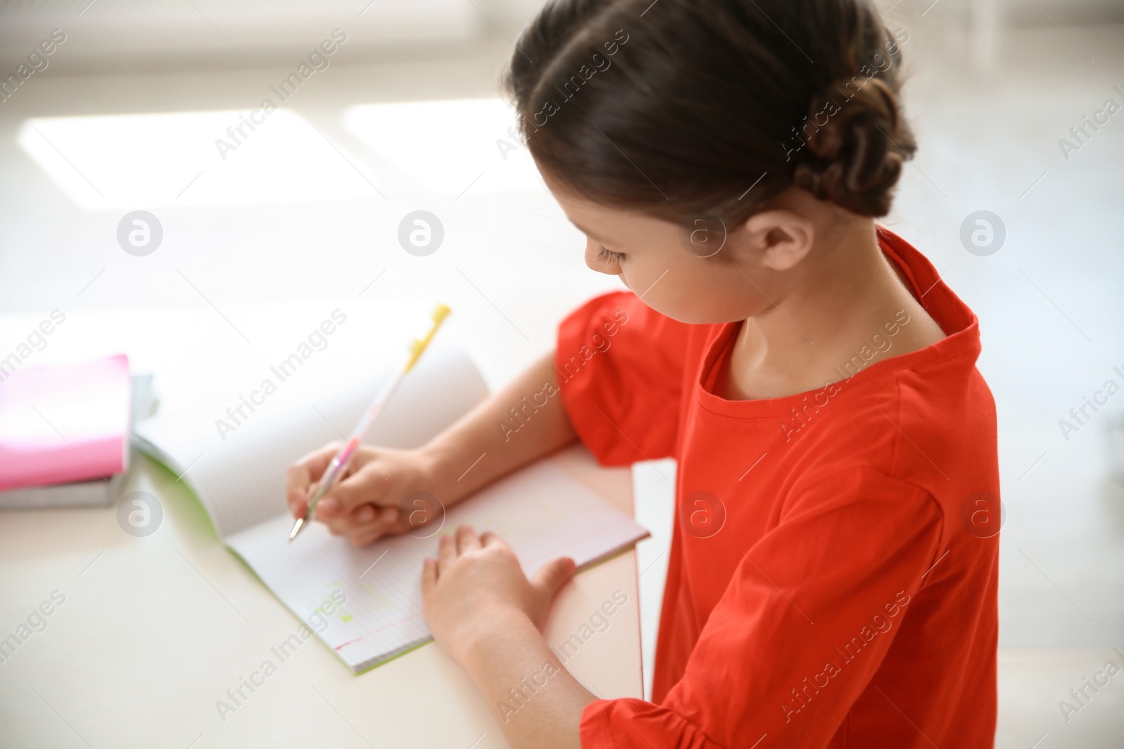 Photo of Cute little child doing assignment at desk in classroom. Elementary school