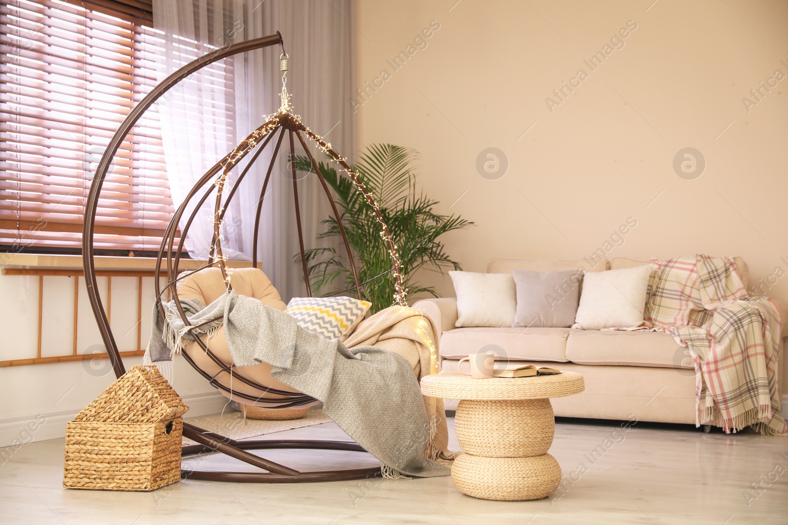 Photo of Cozy hanging chair with fairy lights in modern living room. Interior design