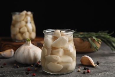 Photo of Composition with jar of pickled garlic on grey table against black background