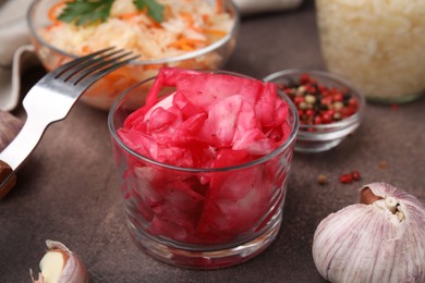 Photo of Delicious sauerkraut and spices on brown table, closeup